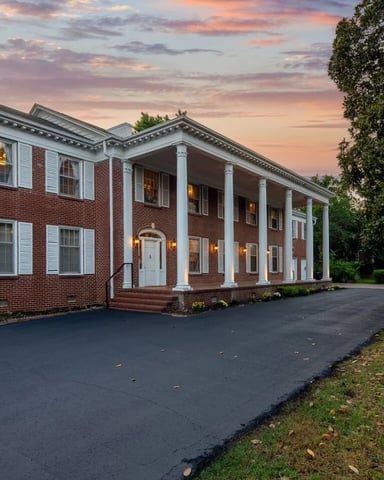 Beland Mansion red brick colonial with white columns at dusk, Fort Smith, AR